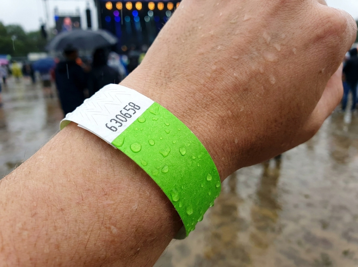 Pulseira de identificacao usada no pulso sob a chuva durante um festival ao ar livre, ilustrando sua resistencia a agua e a umidade