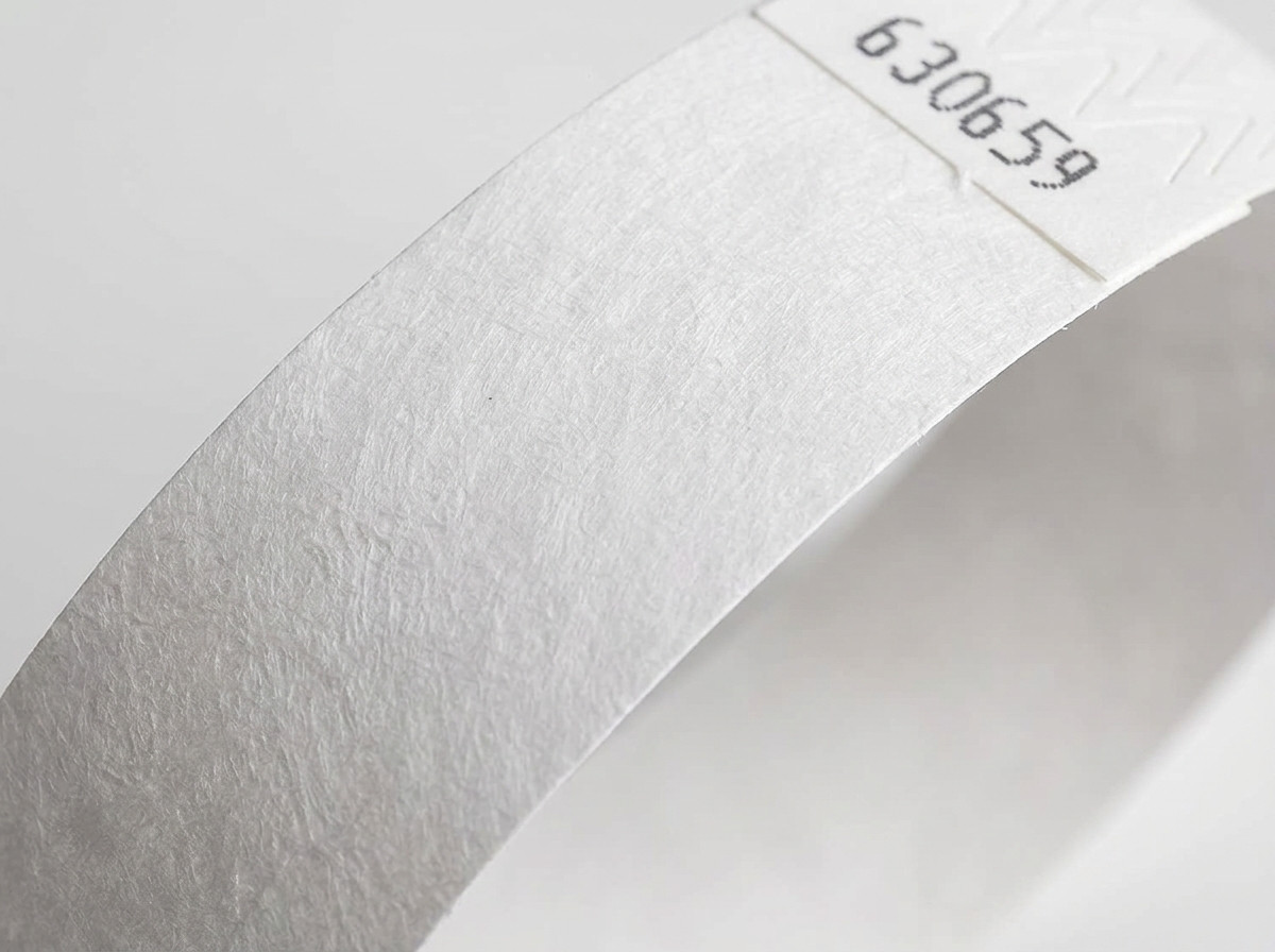 Plano aproximado da superfície não tecida de uma pulseira Tyvek branca, mostrando a textura característica do polietileno de alta densidade